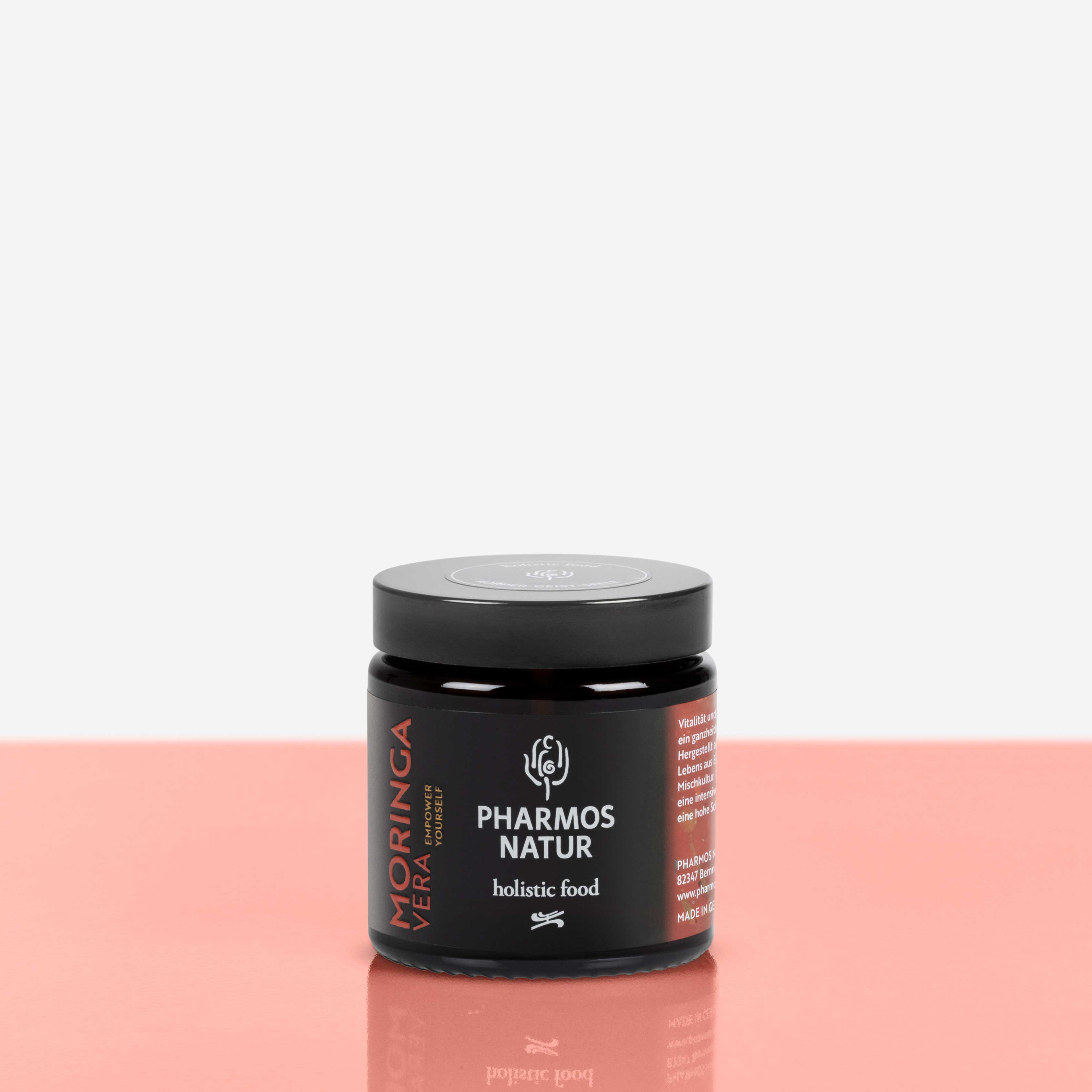 Moringa Vera dunkler Behälter Produktbild neben Pulver und Verpackung